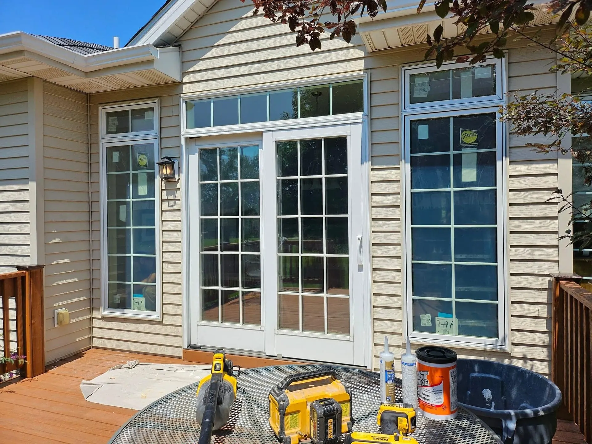 Newly installed white French patio doors on a tan-sided home, viewed from the deck.